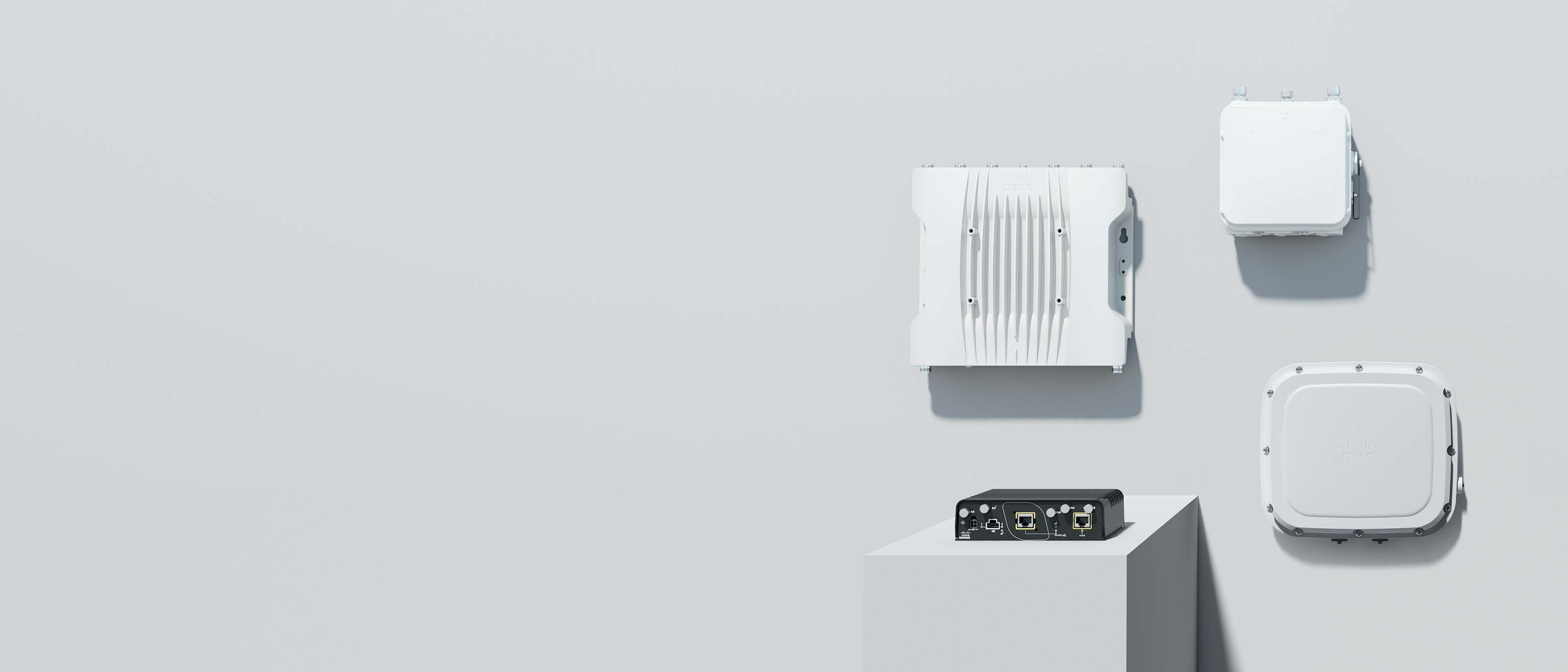 Cisco outdoor and industrial wireless routers. Three are mounted on the wall, one sits on a platform.