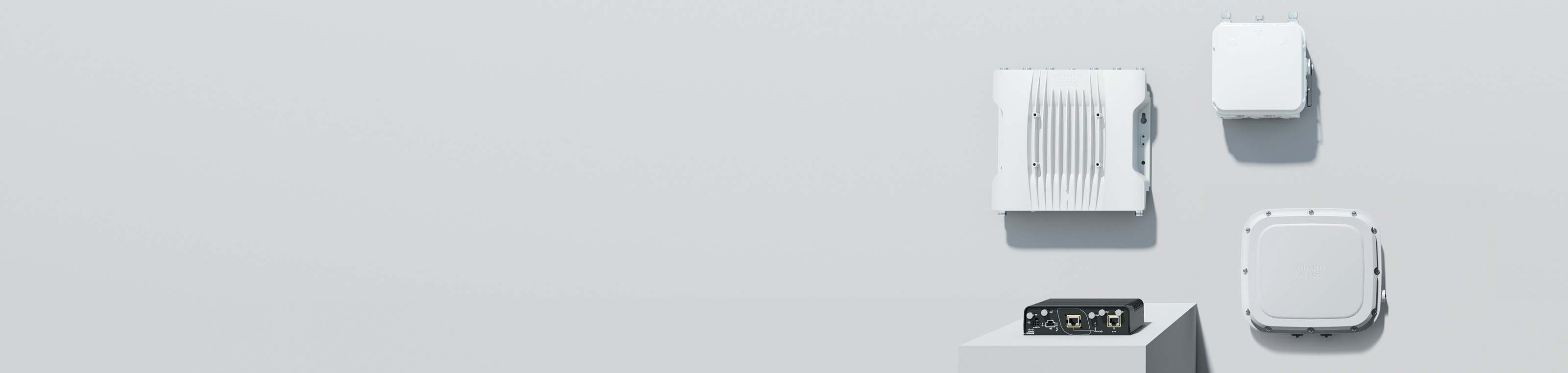 Cisco outdoor and industrial wireless routers. Three are mounted on the wall, one sits on a platform.