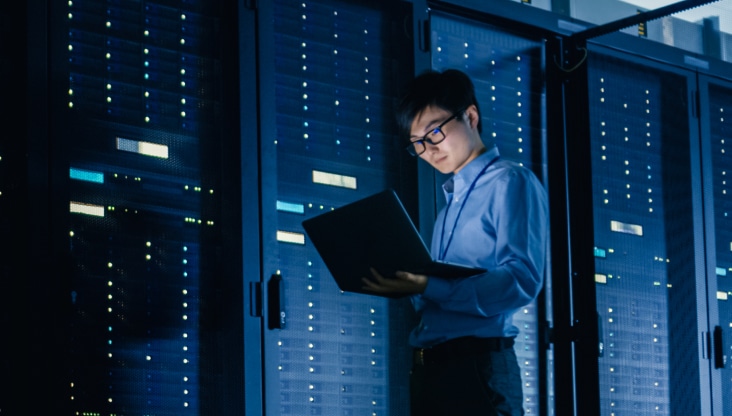 Employee looking at laptop in a data center warehouse