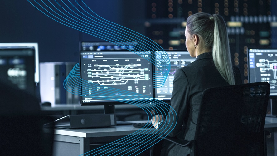 Mitarbeiterin, die an einem Schreibtisch mit zwei großen Monitoren arbeitet