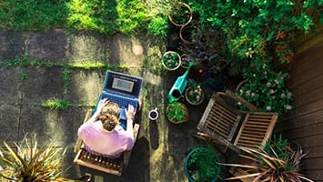 Person working on laptop in garden setting