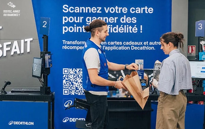 Decathlon associate assists with check out